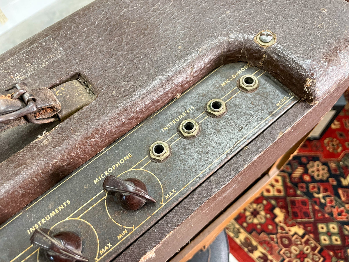 Close-up of the amp's worn brown leatherette top and control panel, showing two brown knobs, four input jacks, and a leather handle.