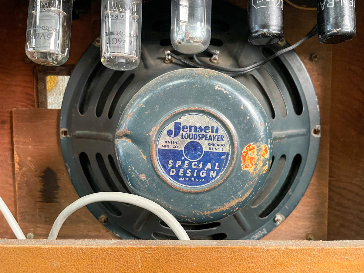 Close-up of the amp's internal speaker, showing its dark gray cone, blue label, and three vacuum tubes above, all with visible wear.