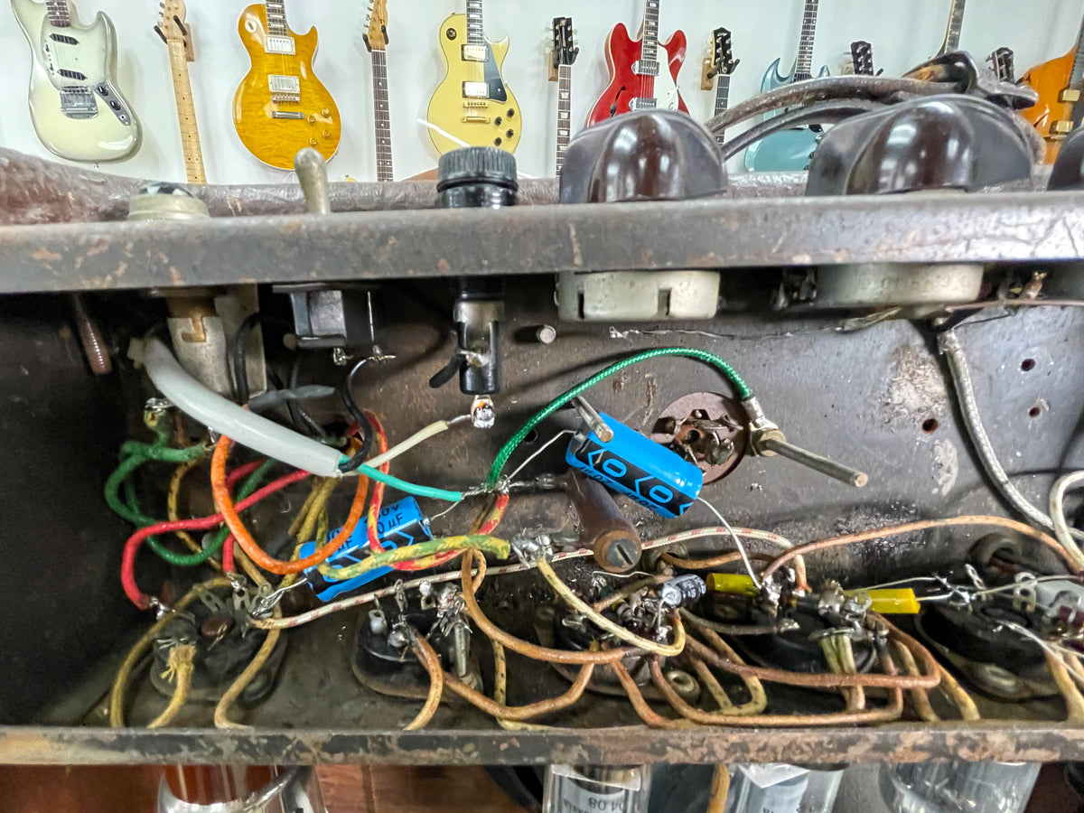 An overhead view of the amp's internal wiring, showing colorful wires, capacitors, and tube sockets, with some dust and wear.