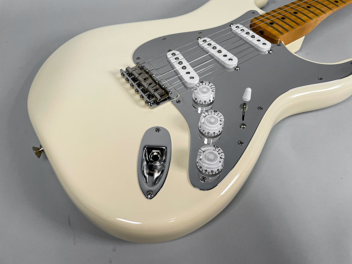 Close-up of the Olympic White Stratocaster body, showing the chrome pickguard, three white single-coil pickups, and three white control knobs.