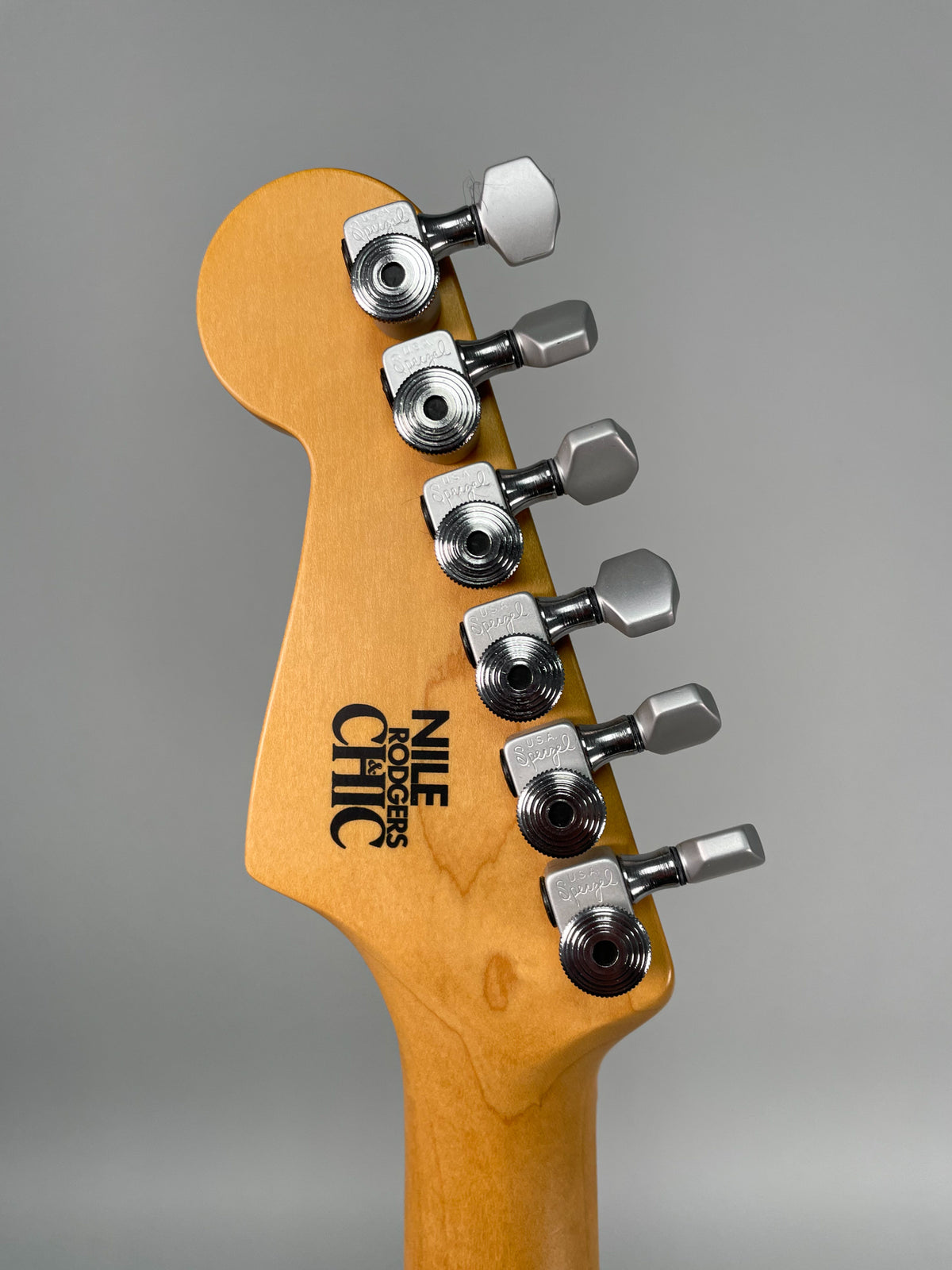Close-up of the headstock from behind, showing the light wood finish and six chrome tuning pegs.