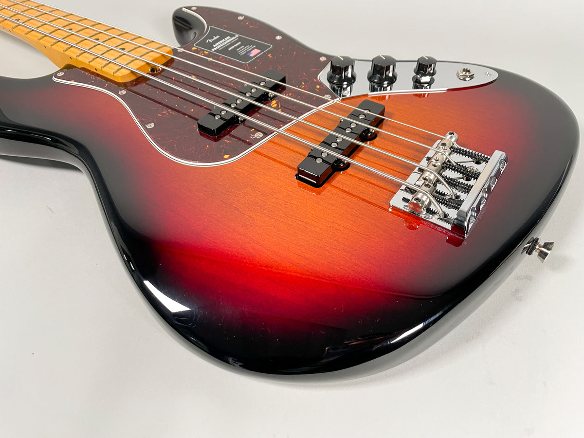 The bass guitar's sunburst body, with a tortoiseshell pickguard, is angled from the lower right, showing the bridge and controls.