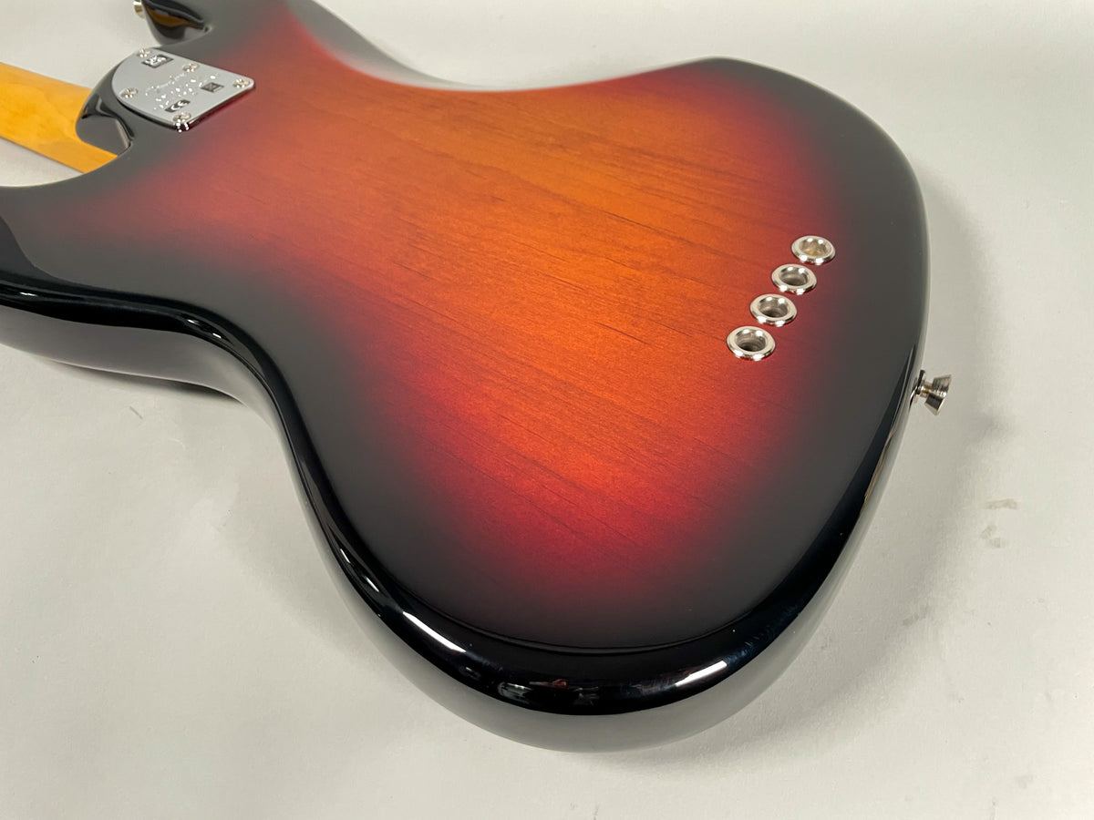 The lower body of a sunburst Jazz Bass, showing the glossy finish, chrome string ferrules, and strap button.