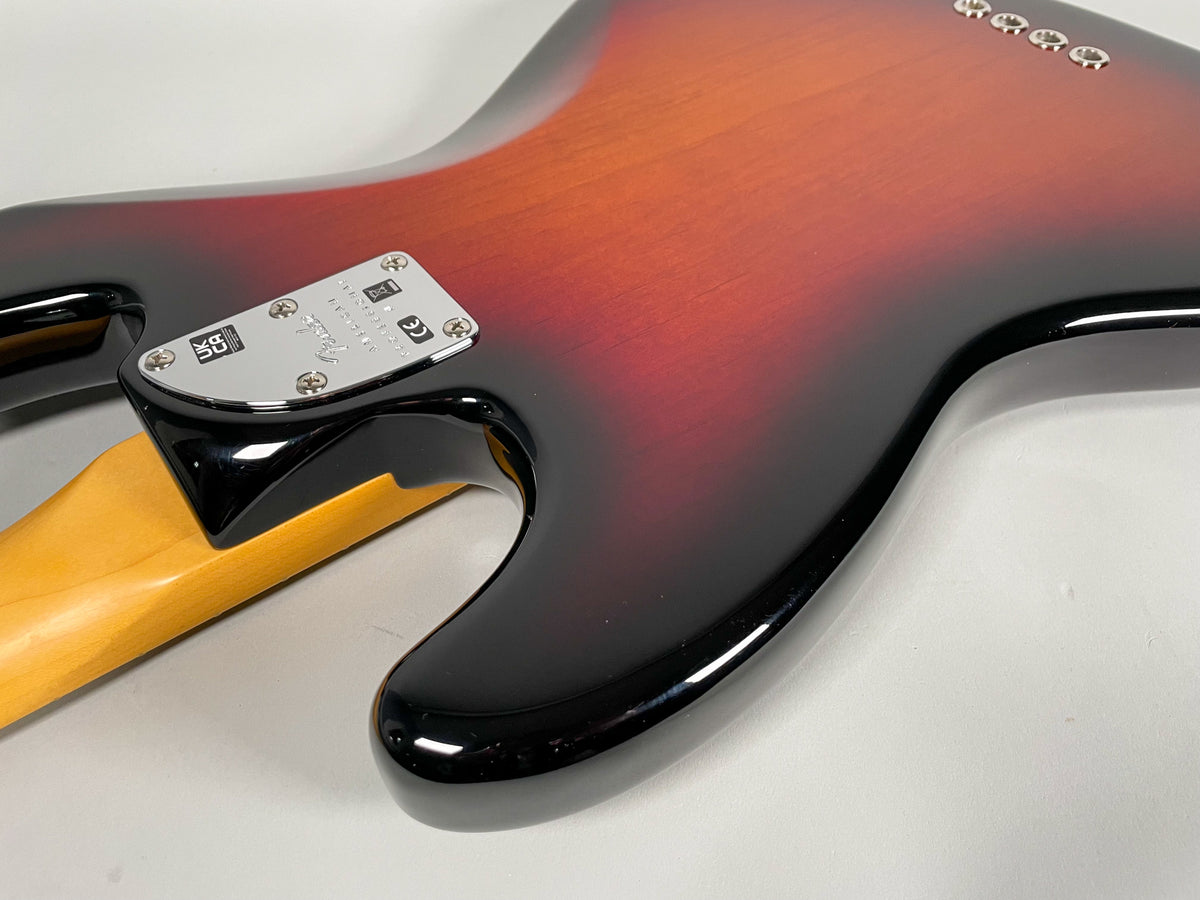 Close-up of the bass guitar's sunburst body and neck joint, showing the chrome neck plate and the glossy finish with no visible wear.