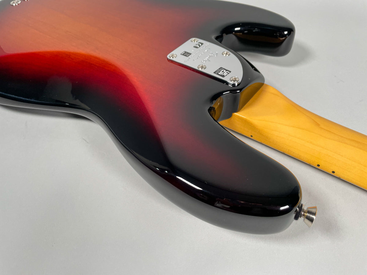 Close-up of the bass's lower body and neck joint, showing the glossy sunburst finish, chrome neck plate, and strap button.