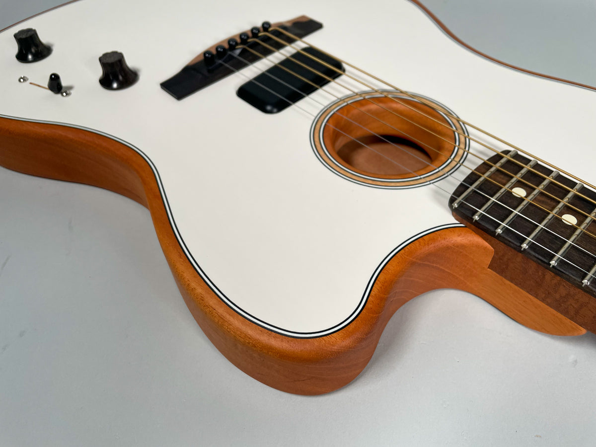 Close-up of the guitar's upper body, showing the white top, natural wood sides, soundhole, bridge, controls, and part of the fretboard.