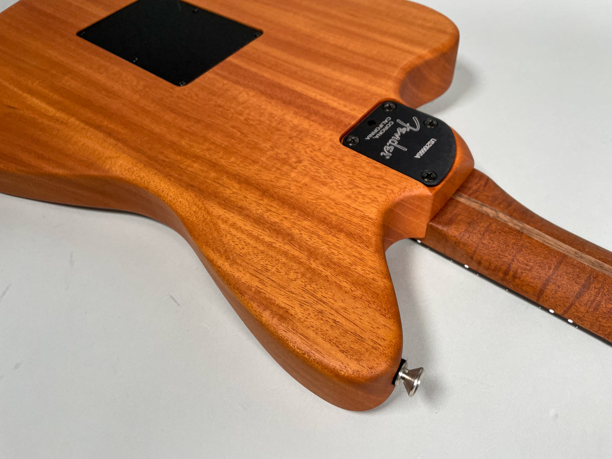 View of the guitar's back, showing the natural wood grain, black neck plate, and a chrome strap button on the lower bout.