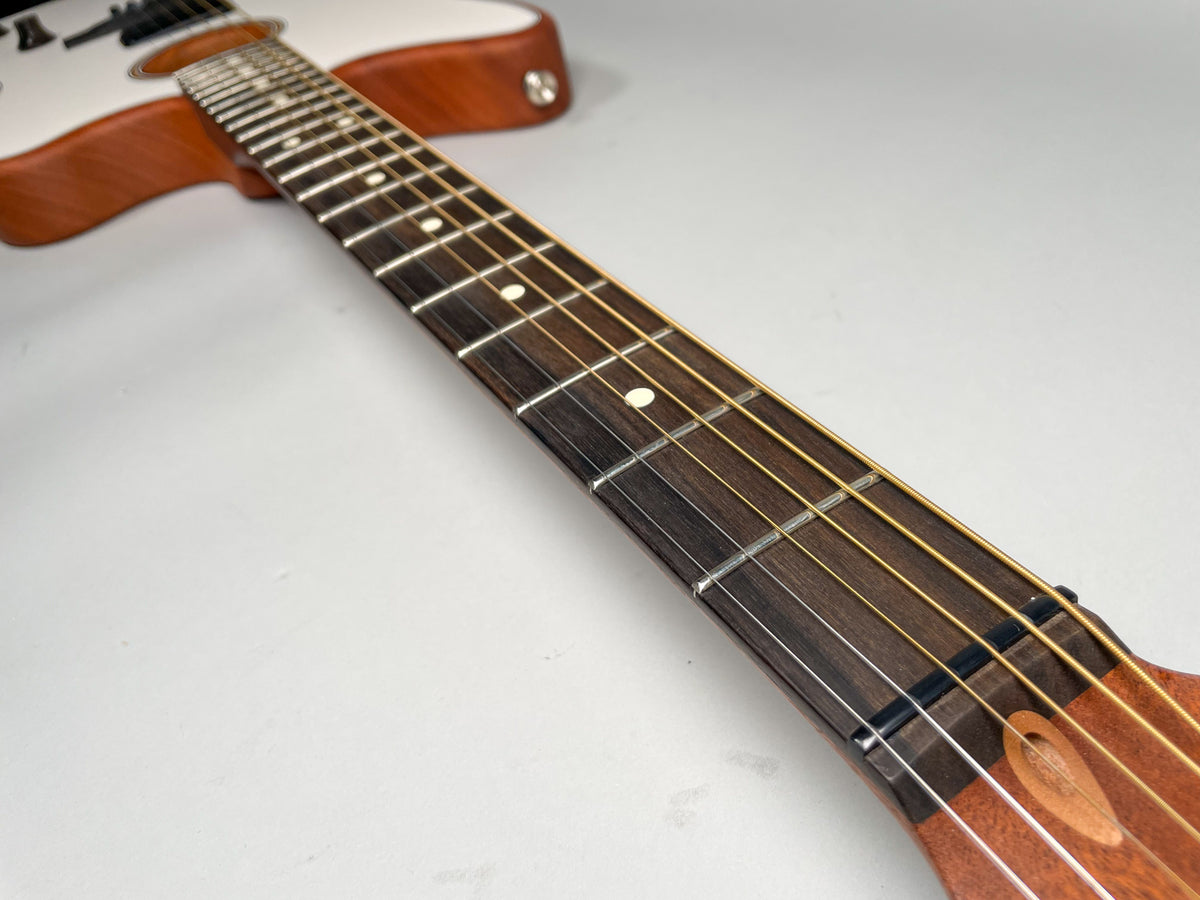 The guitar's dark fretboard with white dot inlays is angled, showing the light wood body and white top in the background.
