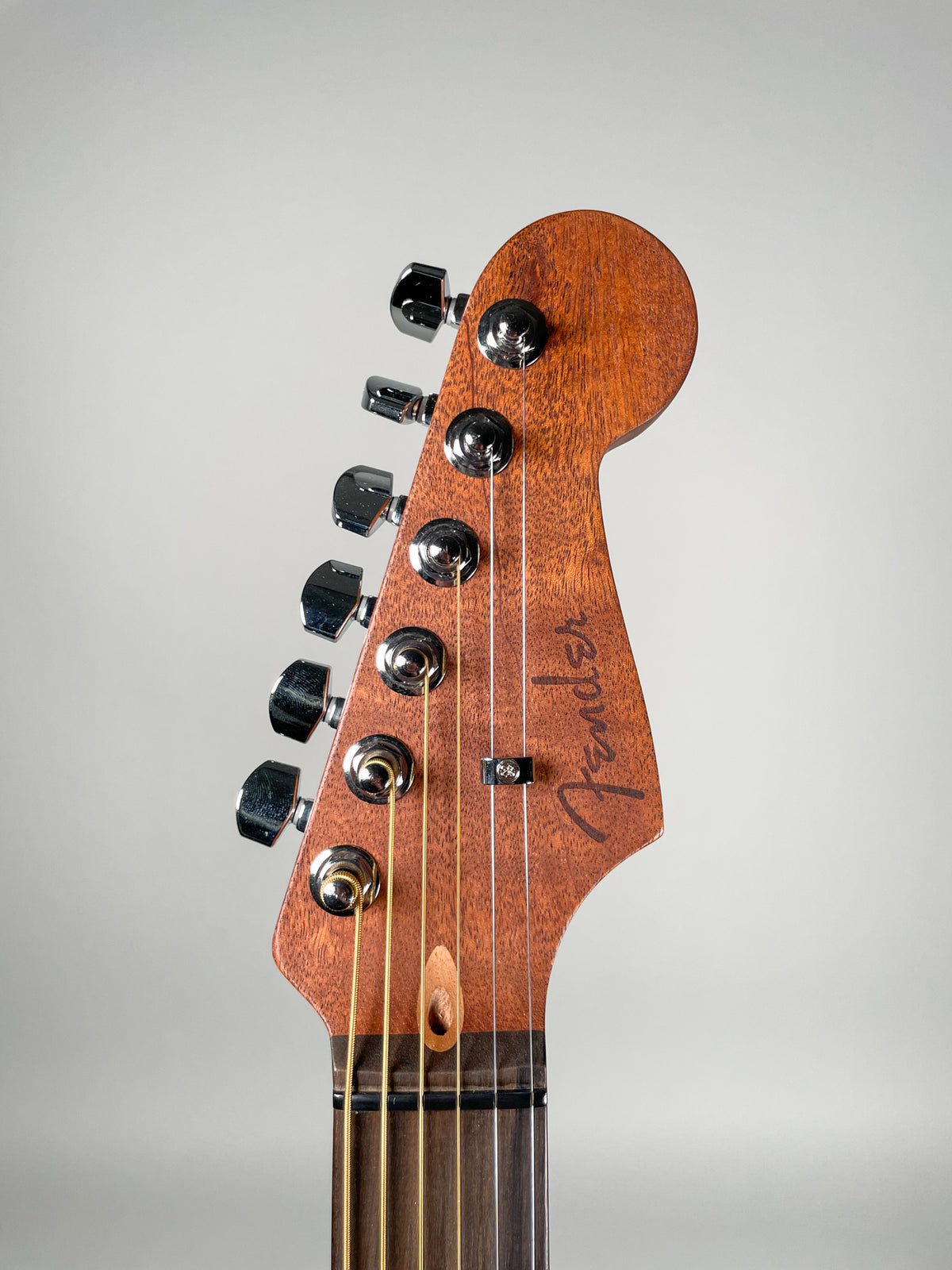 The guitar's headstock, angled left, shows a natural wood grain finish, six chrome tuners, and a dark fretboard.