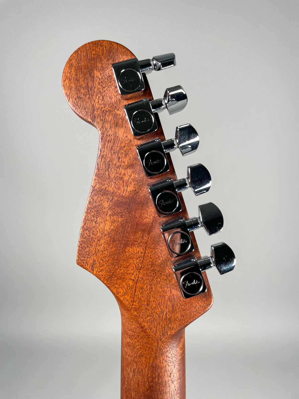 The guitar's headstock and top of the neck, viewed from the rear, showing the natural wood grain and six chrome tuning machines.