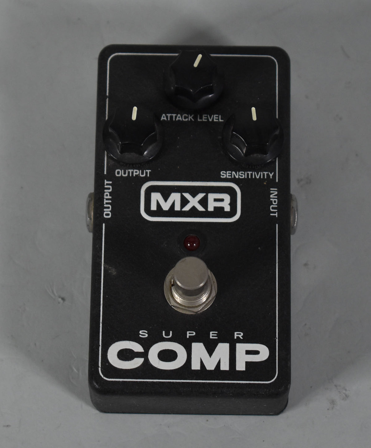 A black rectangular guitar pedal with three black control knobs, a red indicator light, and a silver footswitch.
