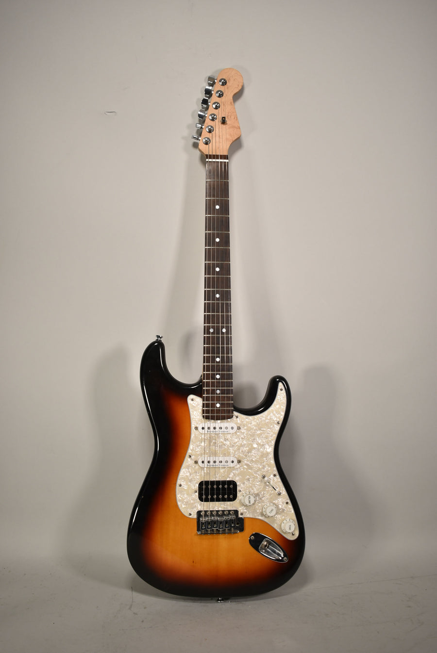Full-length view of a sunburst Strat-type guitar with a pearloid pickguard, HSS pickups, and a natural finish headstock.