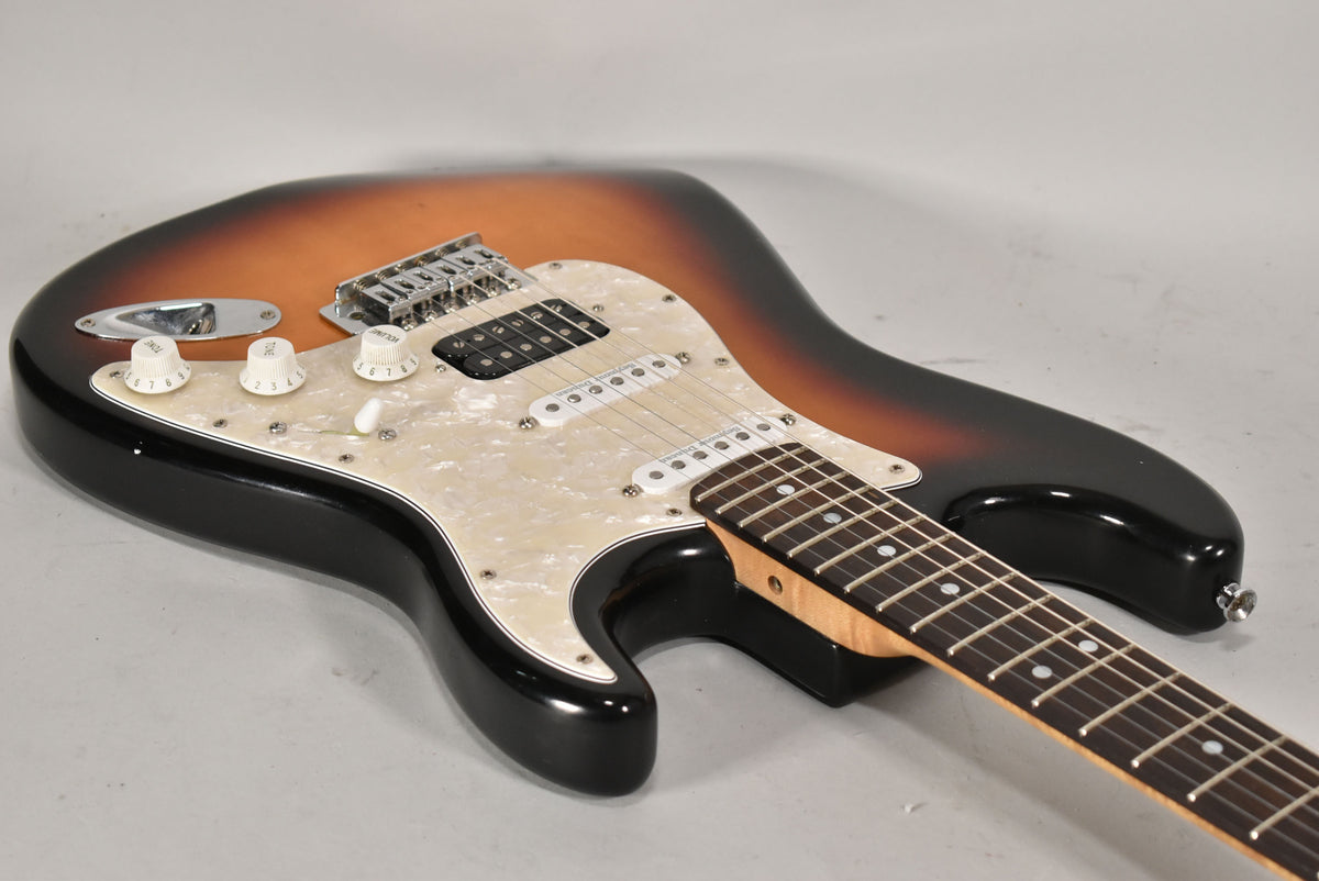 Sunburst Strat-type electric guitar, angled view of the body and neck, showing a pearloid pickguard and HSS pickups.