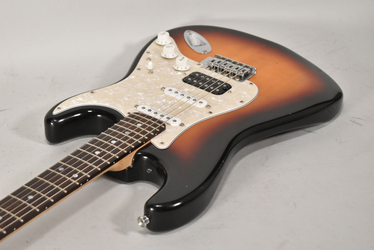 This sunburst Strat-type guitar is angled from the neck, showing its pearloid pickguard, HSS pickups, and three white control knobs.