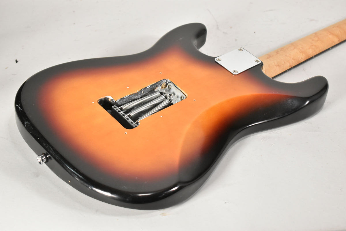 The guitar's sunburst back shows a tremolo spring cavity with three springs, a neck plate, and wear along the bottom edge.
