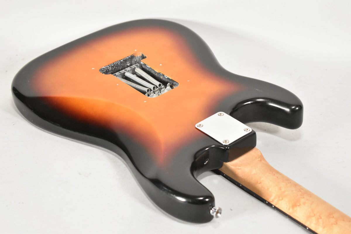 The guitar's sunburst back shows a tremolo cavity with springs, a chrome neck plate, and a light maple neck.