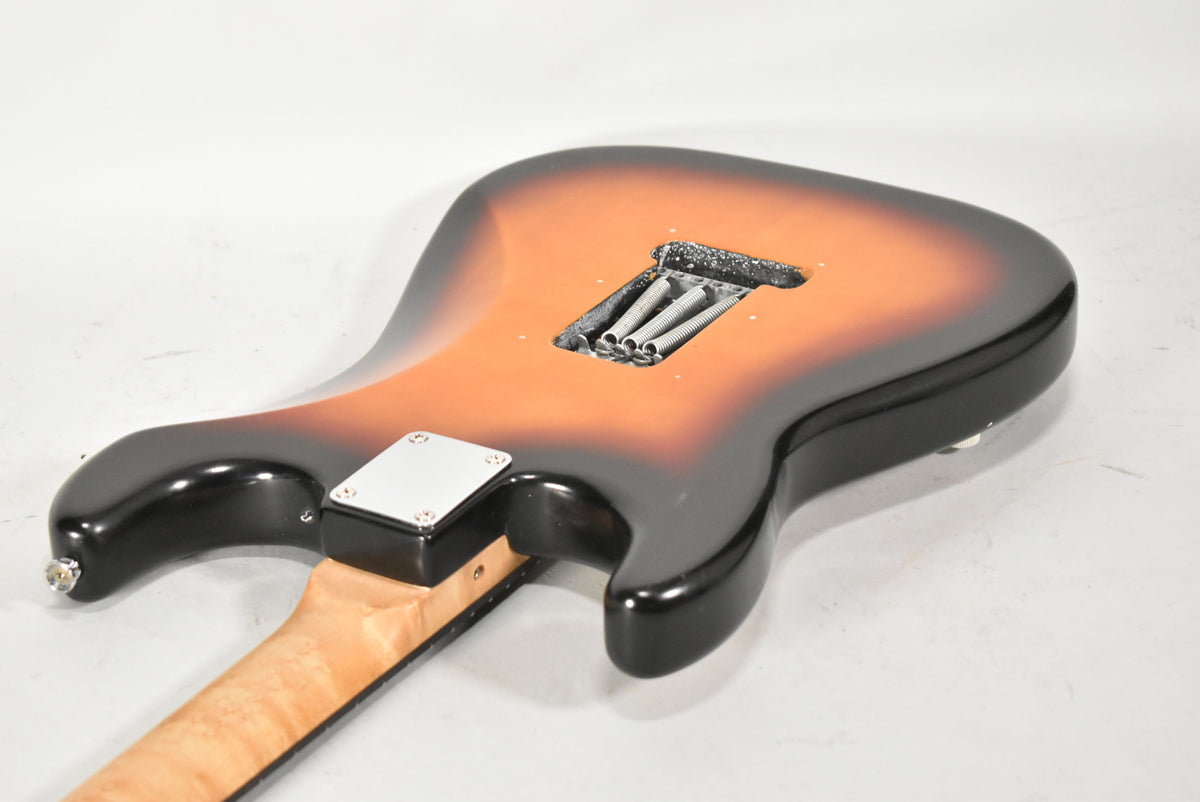 The guitar's sunburst back shows a tremolo spring cavity with three springs and a chrome neck plate, with a maple neck.