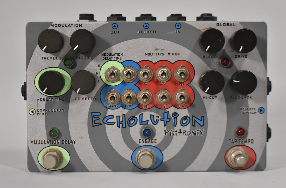 Top-down view of a gray pedal with a spiral design, featuring 10 black knobs, 10 small metal toggle switches, and 3 footswitches.