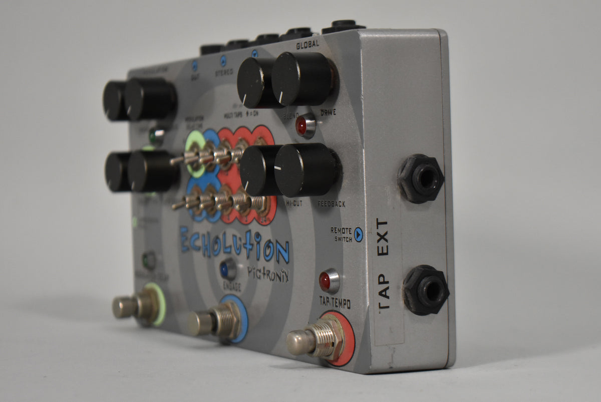 A silver delay pedal, angled to show its top and right side, with black knobs, toggle switches, and two footswitches.