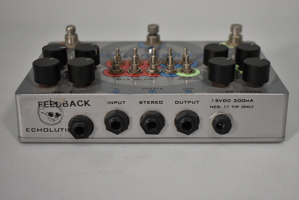 A Pigtronix Echolution V1 pedal with 8 black knobs, 6 toggle switches, and 5 input jacks.