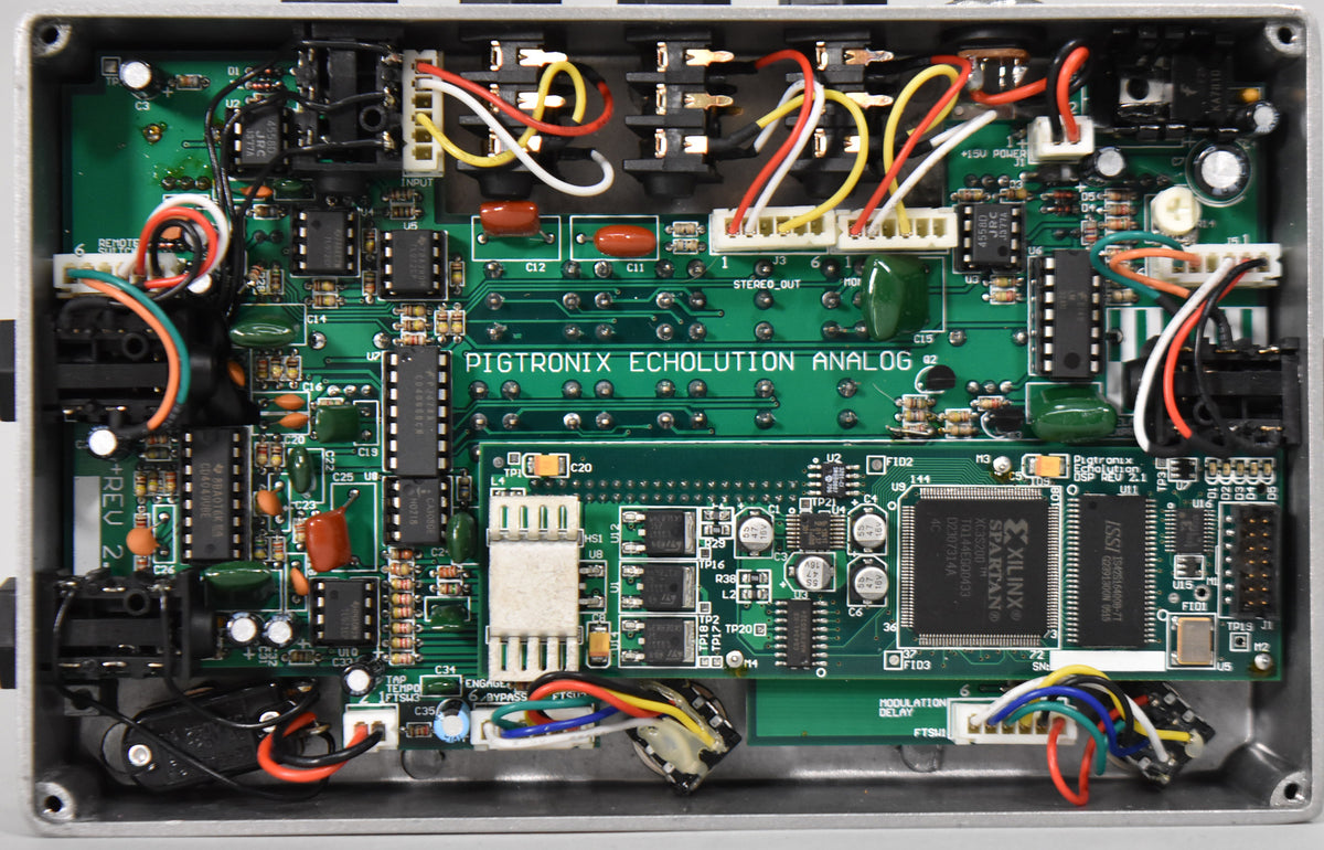 Top-down view of the pedal's open silver enclosure, revealing green circuit boards densely packed with chips, wires, and components.