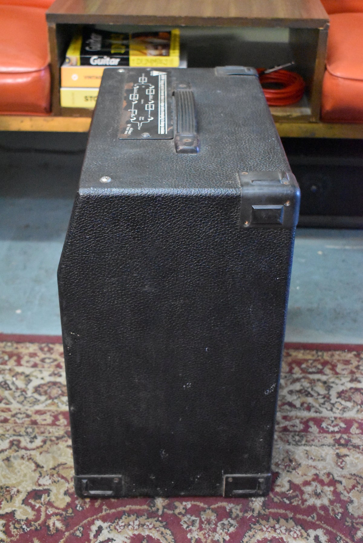 Top-down view of the black textured combo amp, showing the top handle, corner protectors, and some scuffs on the side.