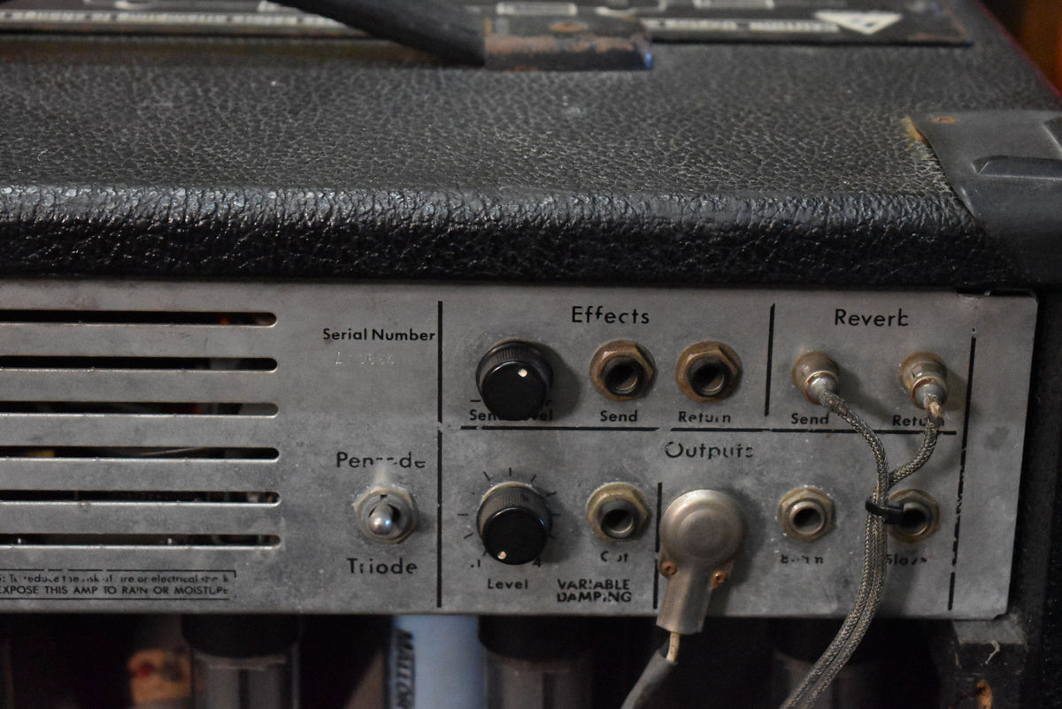 Close-up of the amp's rear panel, showing the silver control plate with black knobs, various jacks, and a toggle switch.