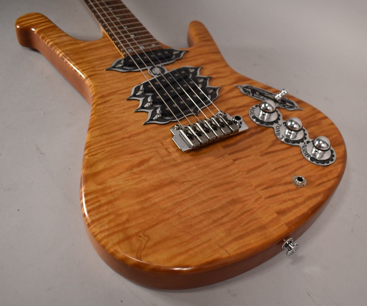 Close-up of the guitar's flamed maple body, showing ornate black pickup surrounds, chrome hardware, and three control knobs.