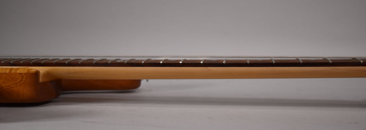 The guitar's light brown neck and dark fretboard are seen from the side, with the body's natural wood grain visible at left.