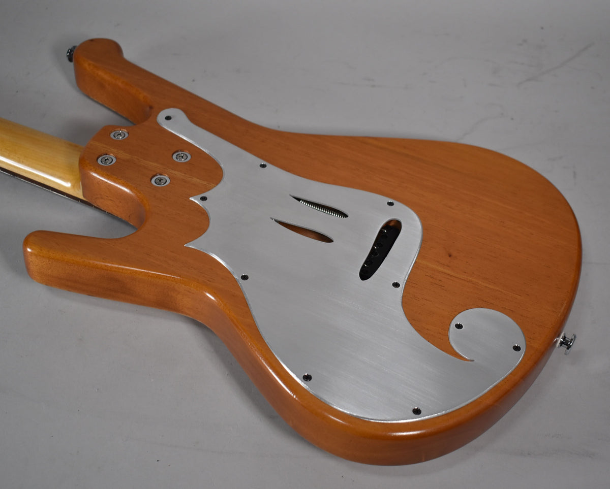 The guitar's natural wood body with a glossy finish is seen from the back, featuring a brushed metal pickguard with cutouts.