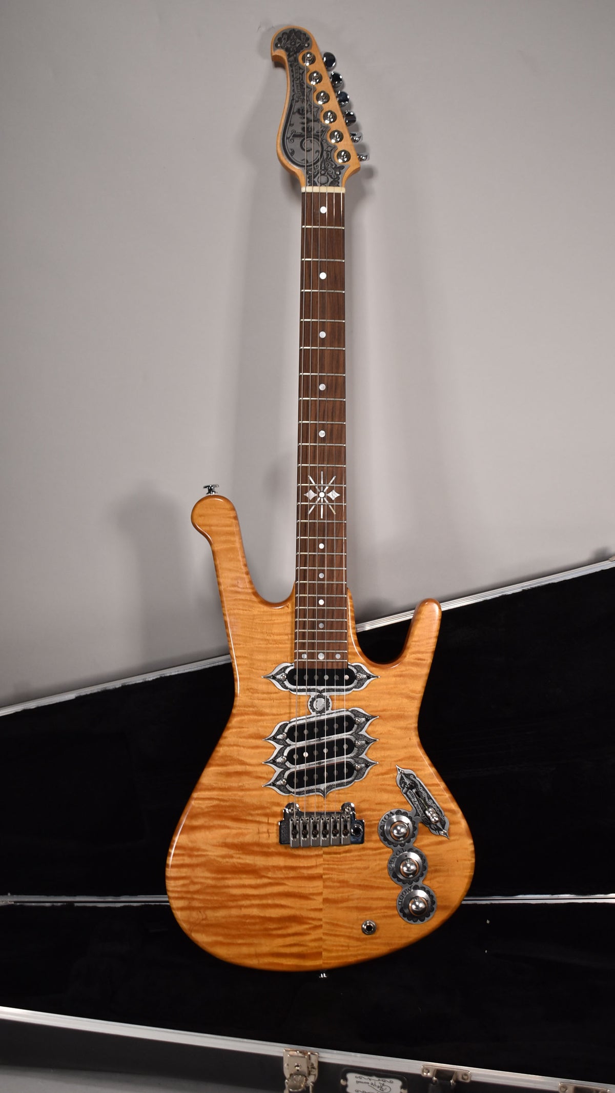 Full view of a natural finish electric guitar with a flamed maple top, ornate metal hardware, and a star inlay at the 12th fret.