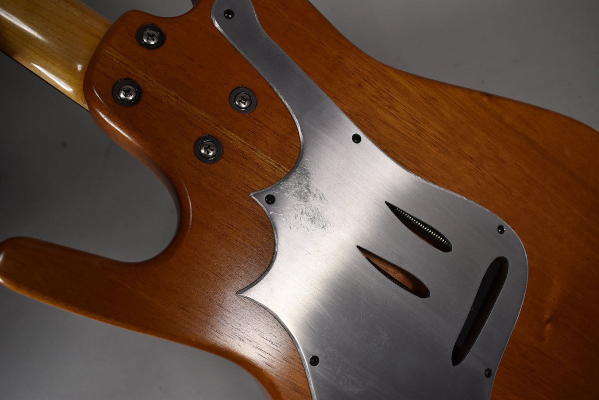 Close-up of the guitar's back, showing the natural wood finish, a brushed metal control plate with three slots, and light wear.