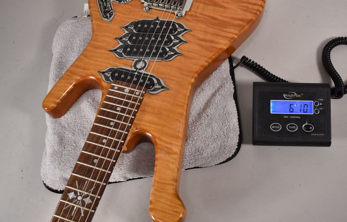 The natural finish electric guitar, with ornate pickup surrounds, rests on a towel next to a scale displaying "6.10".