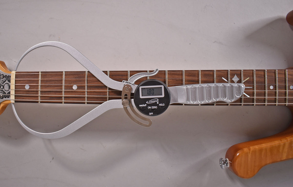 A digital fret height gauge measures 1.80mm on the rosewood fretboard with dot inlays and ornate fret markers.