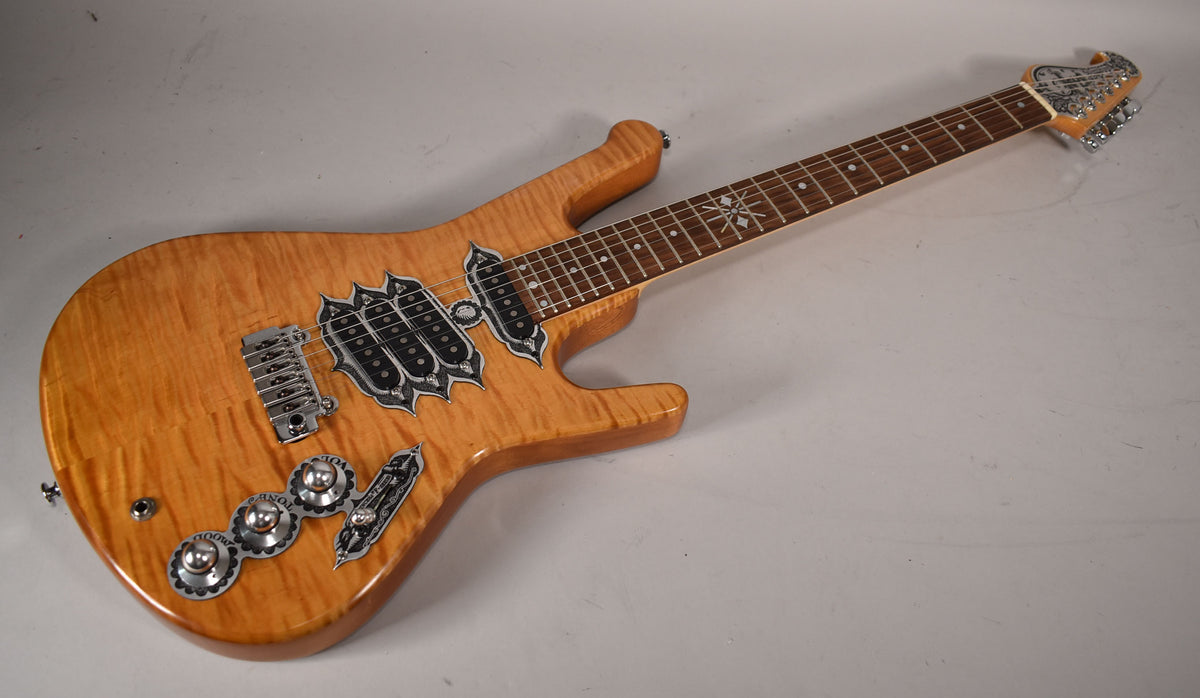 Full guitar, angled from above, showing the natural flame maple finish, ornate chrome hardware, and snowflake fret inlays.