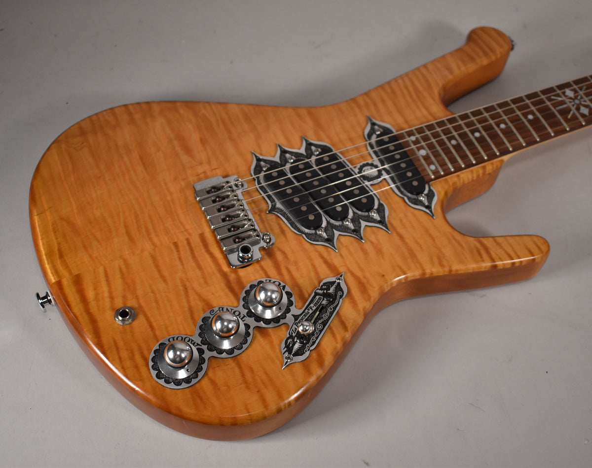 The natural finish electric guitar's body, with ornate silver hardware, is angled from the lower left to the upper right.