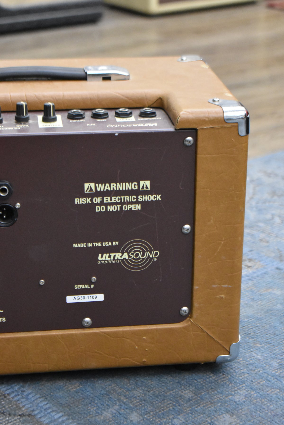 Close-up of the amp's brown control panel and tan tolex side, showing the serial number label and some surface scratches.