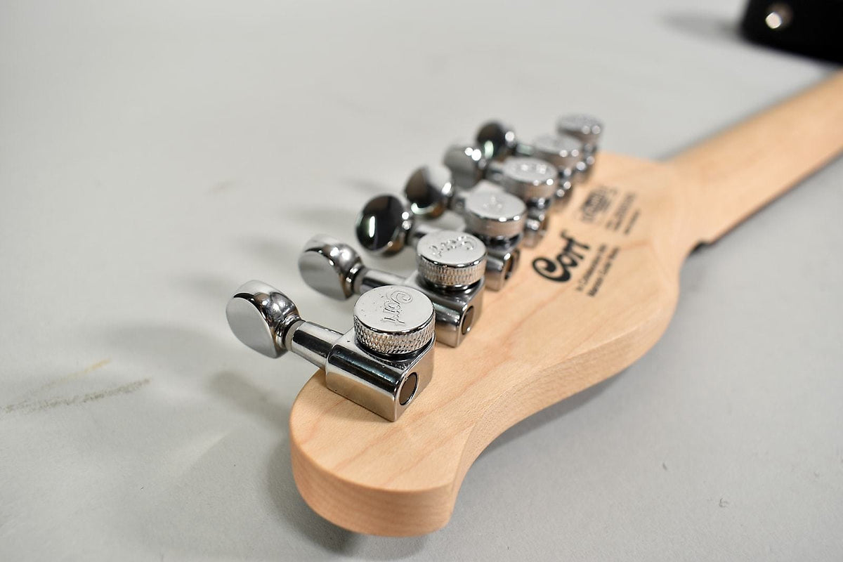 The back of the guitar's natural wood headstock and neck, with six chrome tuning machines.
