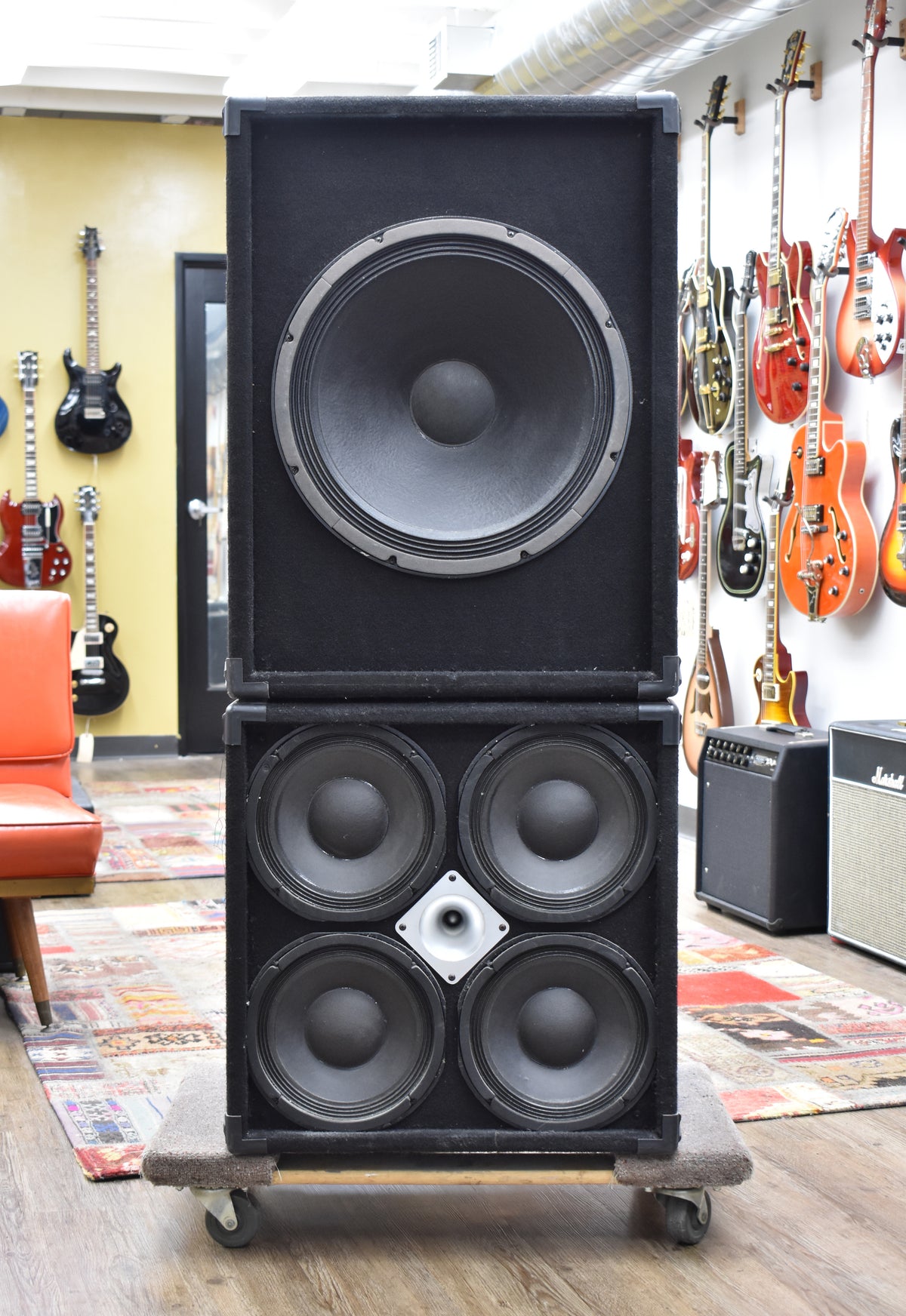 Two black carpeted speaker cabinets, one with a large single speaker, the other with four smaller speakers and a central horn.