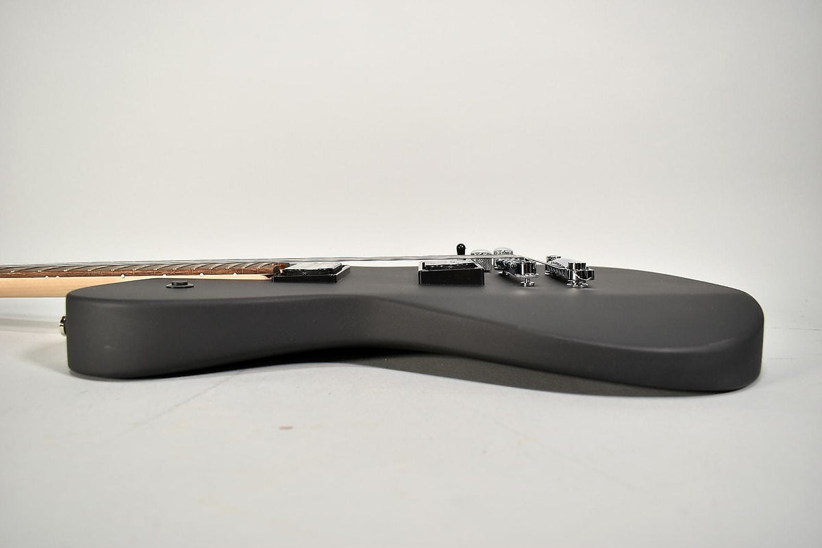 The electric guitar's matte black body is viewed from the side, showing two humbucker pickups and chrome hardware.